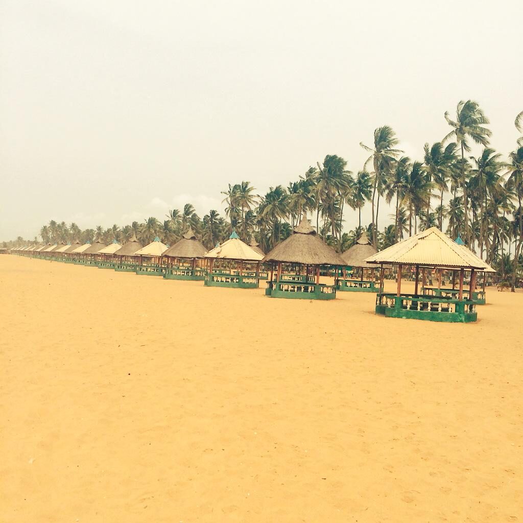 Suntan Beach in Badagry with a line of gazebos and coconut trees.